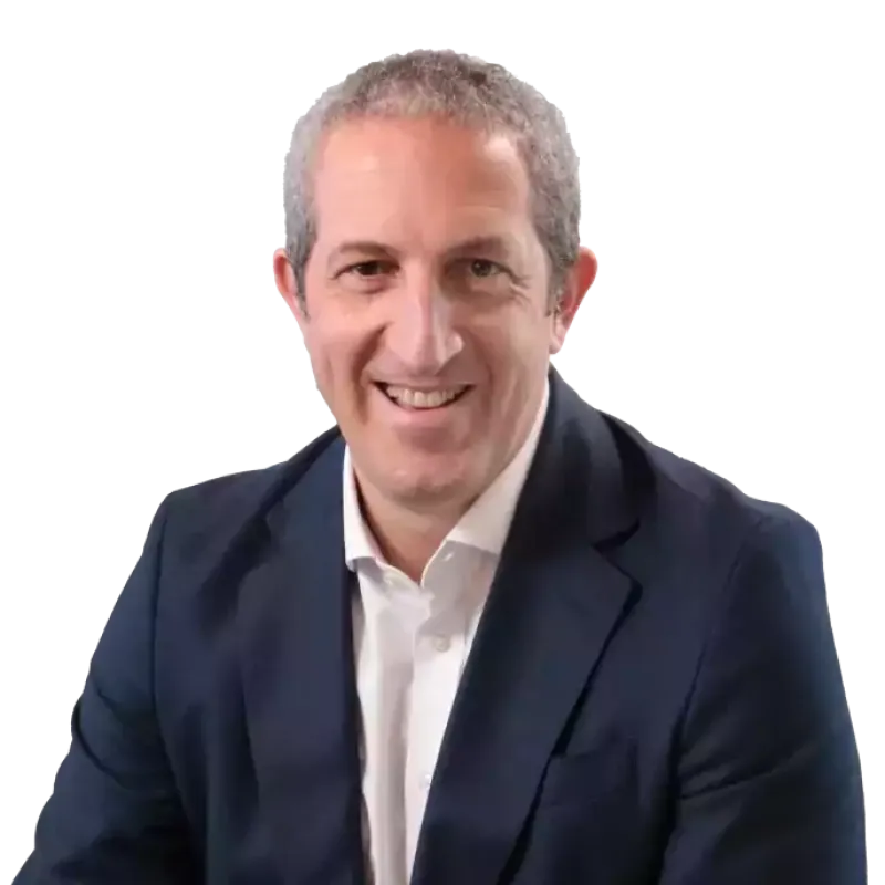 Smiling man with short gray hair wearing a navy blue suit jacket and white shirt, seated and facing the camera against a plain background. Javier Dib.